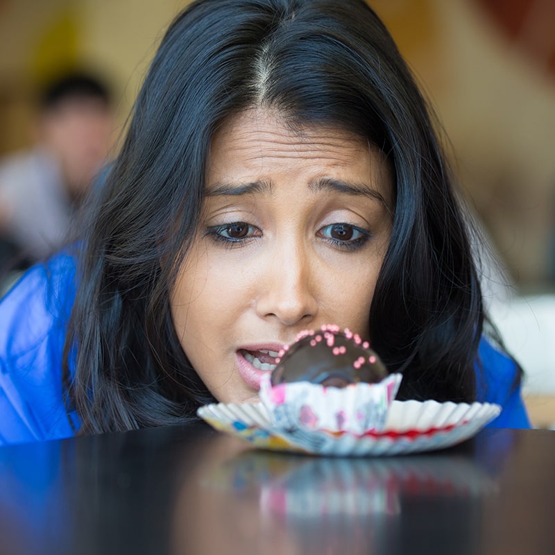 image of a woman longlingly staring at a cupcake